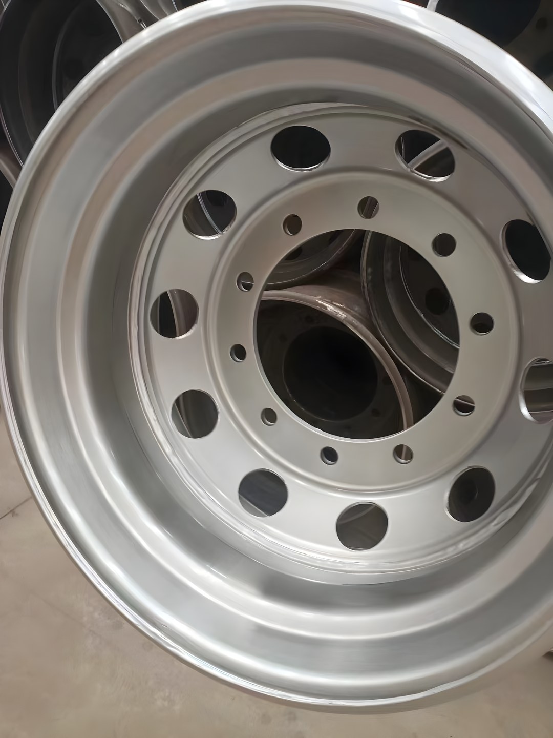 Silver-finished tubeless steel truck wheel seen from the disc side, showing the rim flange, ten hand-holes and ten stud holes